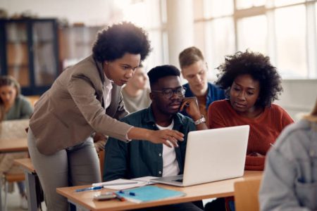 African American professor and her students using laptop during lecture in the classroom.